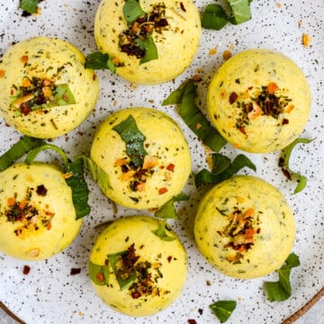 This is an overhead view of the copycat Starbucks egg bites on a speckled plate. They are seasoned with red pepper flakes and basil.