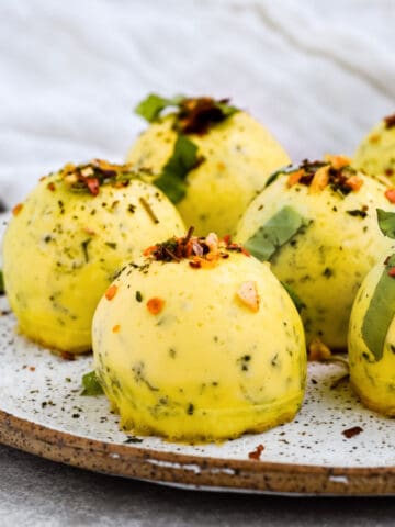This is a side view of the copycat starbucks instant pot egg bites on a speckled plate topped with crushed red pepper flakes and basil.