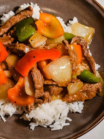 Close up of pepper steak stir fry served over rice.