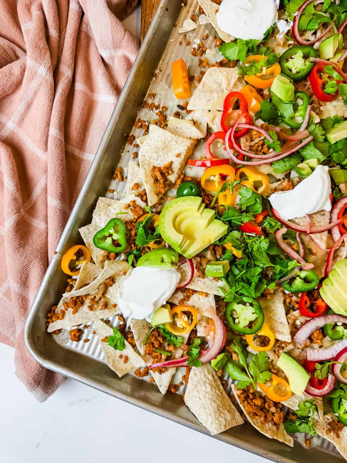 This is a close up of the healthy nachos with a peach kitchen towel in the background. 