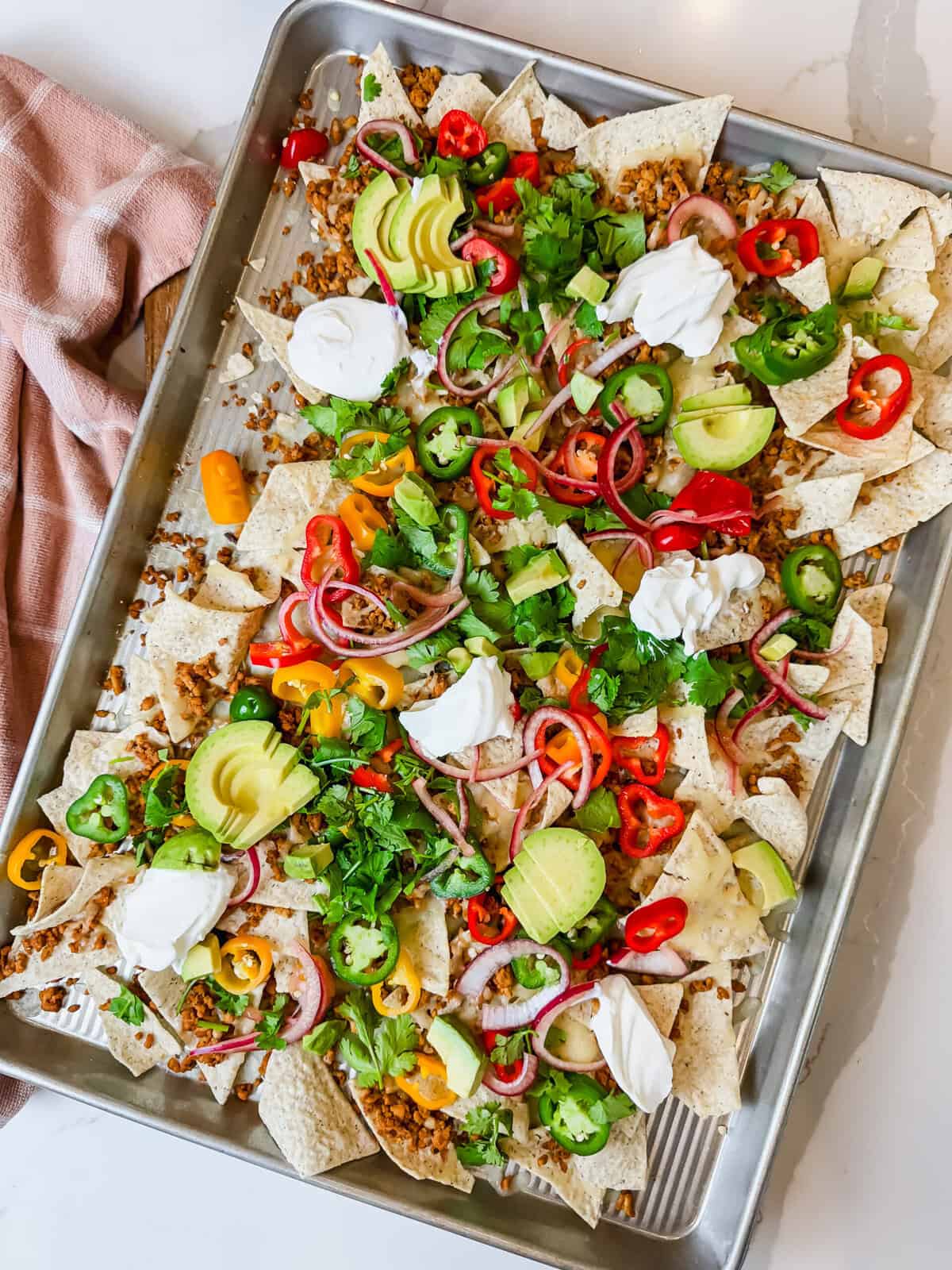 This is a top view of my healthy nachos featuring siete chips, ground chicken with taco seasoning, jalapenos, cilantro, avocado, cheese, pickled onions, peppers and sour cream. 