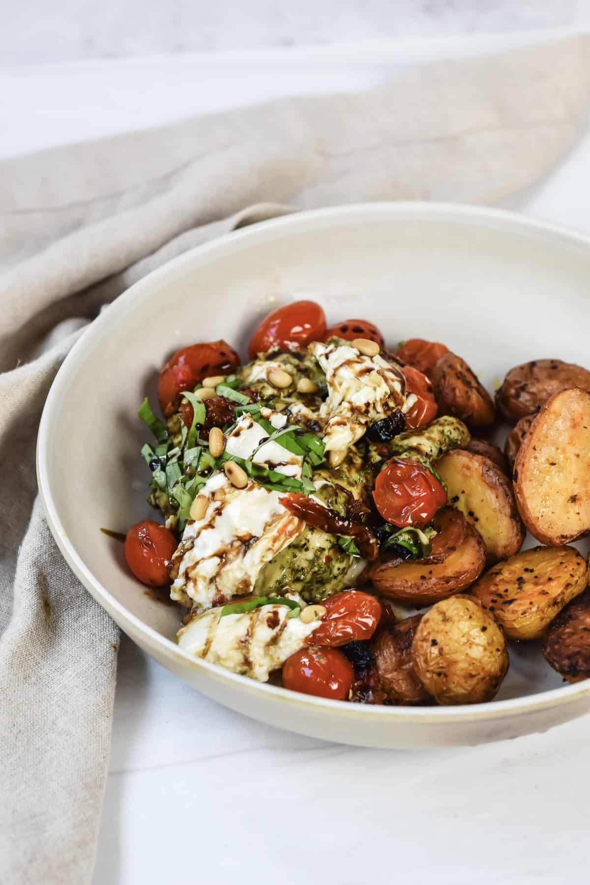 This is a side view of my pesto chicken dish in a bowl with roasted potatoes. 