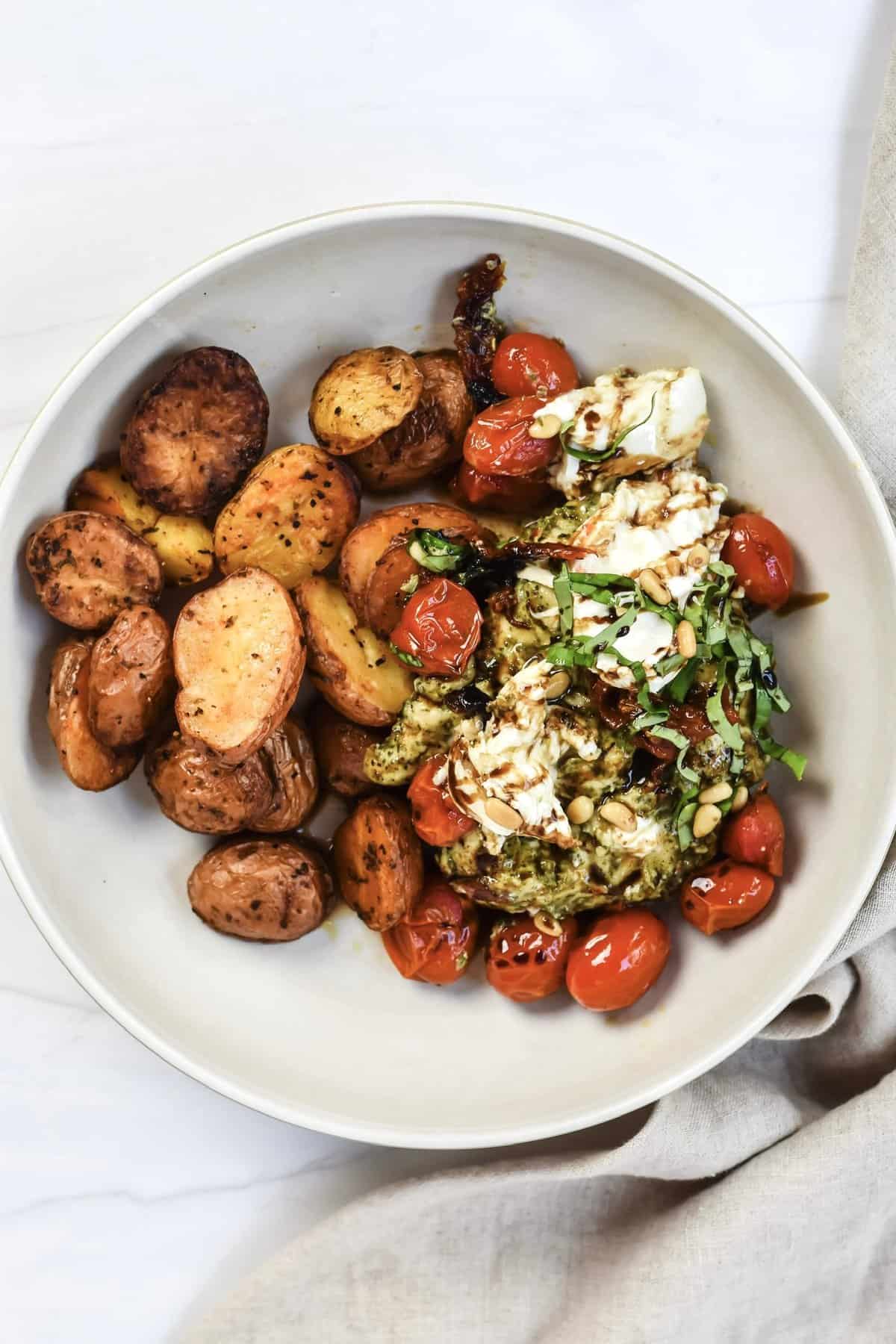 This is a top view close up of my trader joe's pesto chicken recipe on a plate with roasted potatoes. 