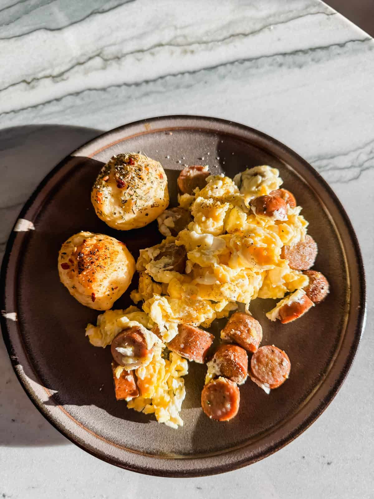 this is a close up of my cottage cheese bagel bites on a plate with some scrambled eggs and maple sausage